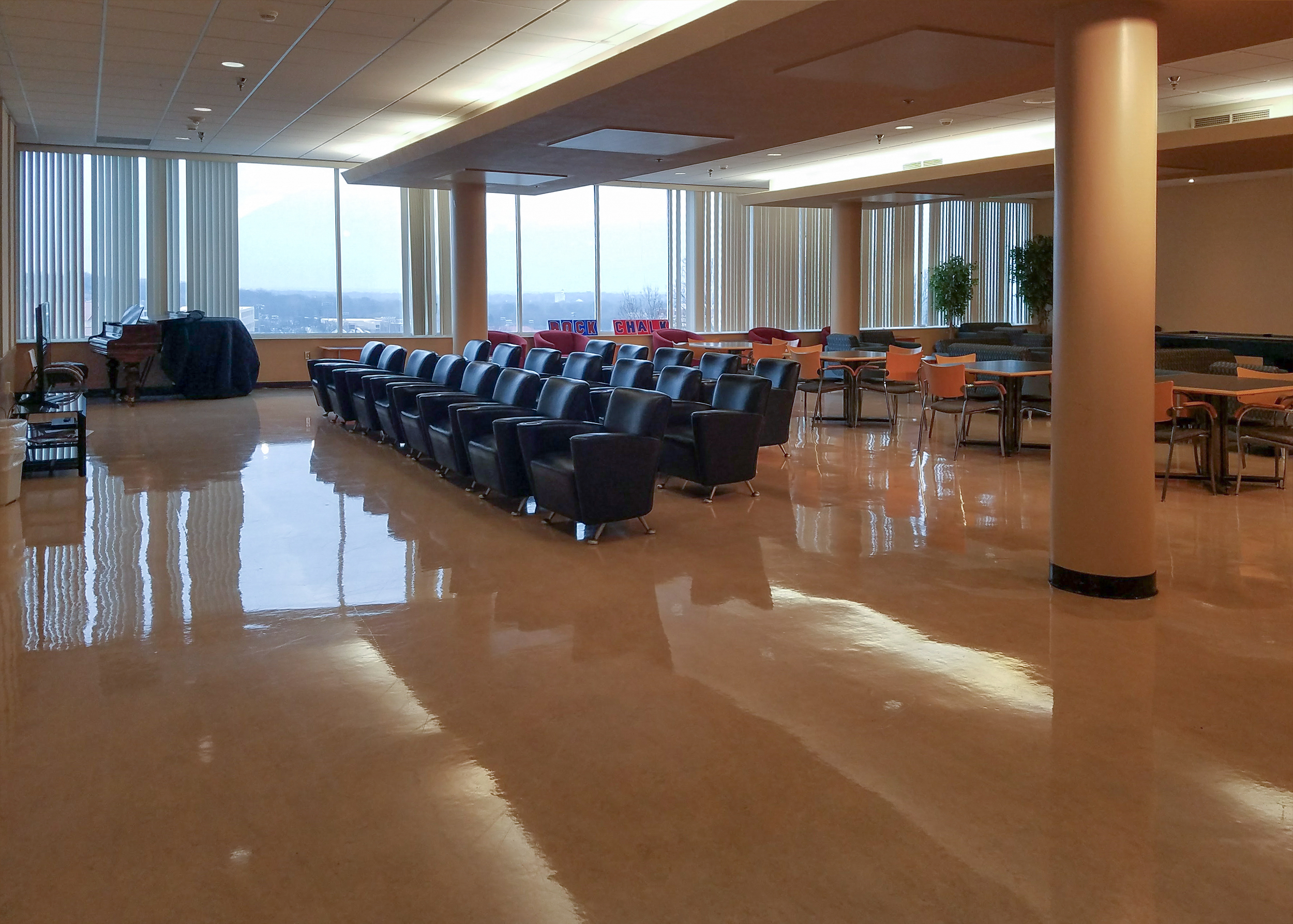 Rows of padded chairs on a polished floor and floor to ceiling windows along the back wall in the Ellsworth Living Room.