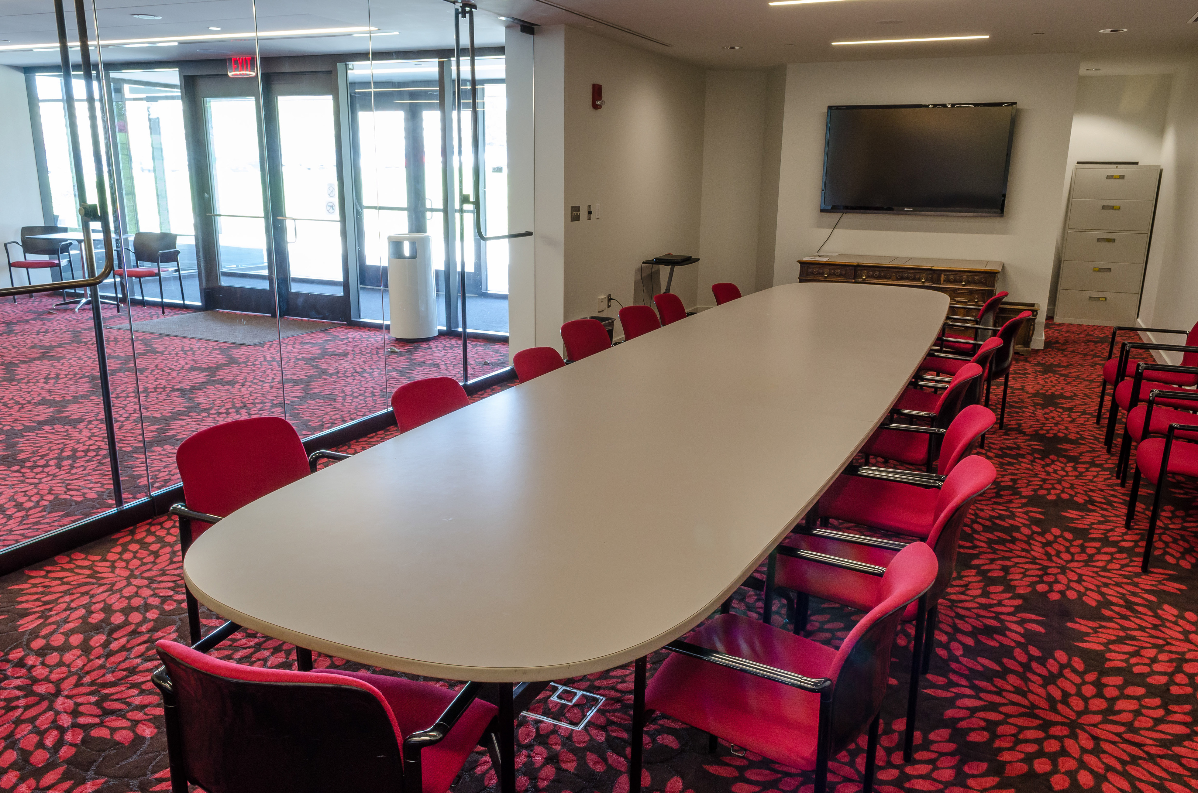 A conference room with a large table, chairs, and a screen.